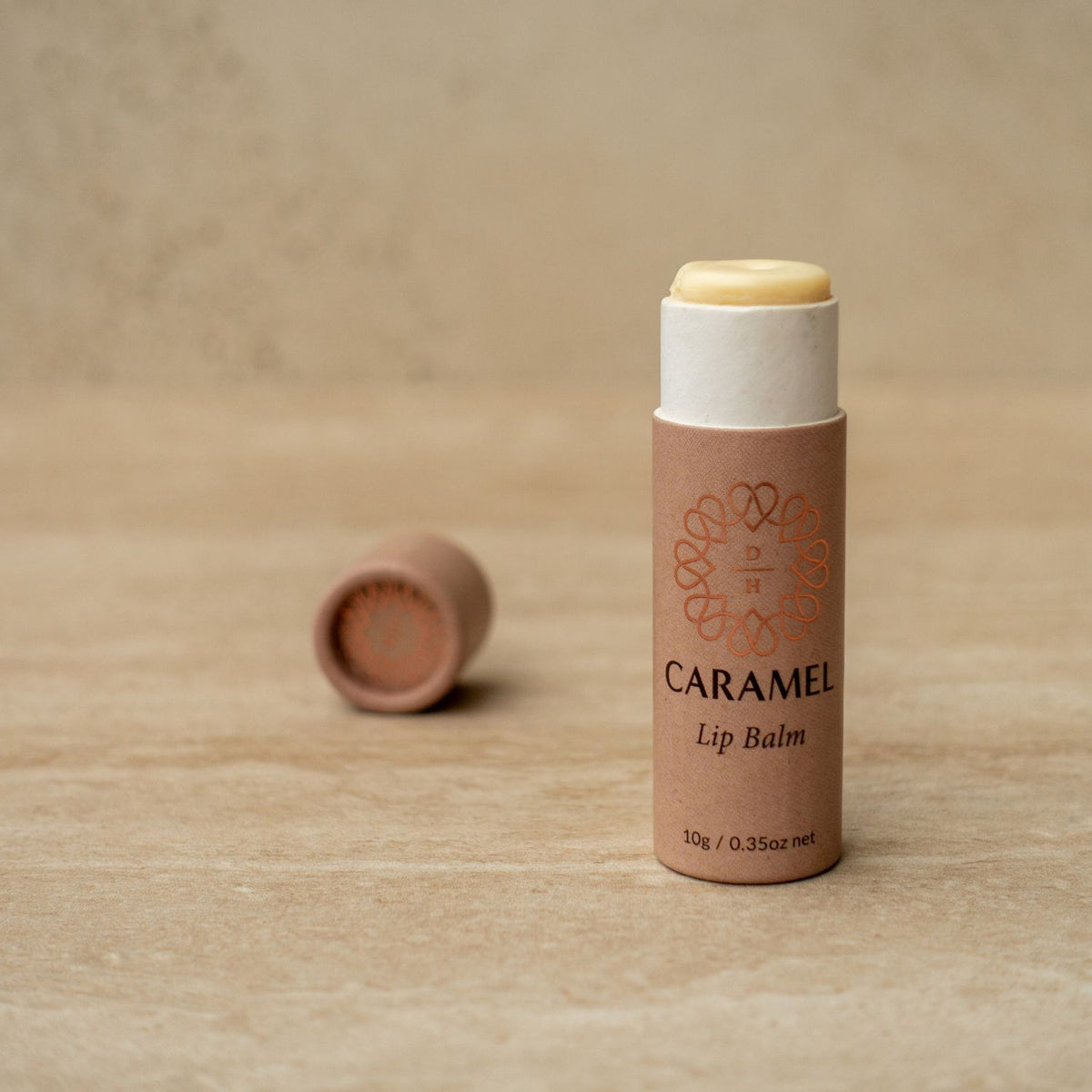 plastic free lip balm in an eco friendly compostable cardboard tube caramel flavour with 100% natural flavour oil and rich creamy cocoa butter made in nz and hand poured